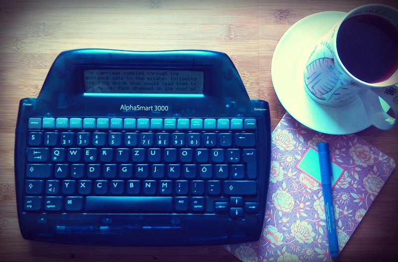 Sandy's author's desk with her AlphaSmart, a notebook, and a cup of tea