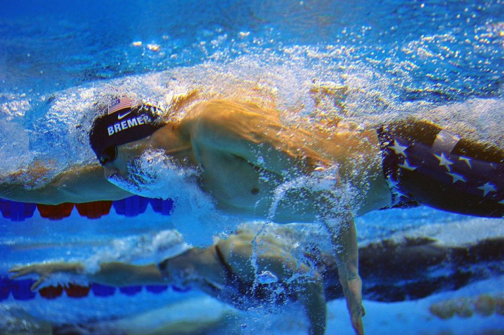 Pair of Olympic swimmers shown in simultaneous action in parallel pool lanes via underwater camera.