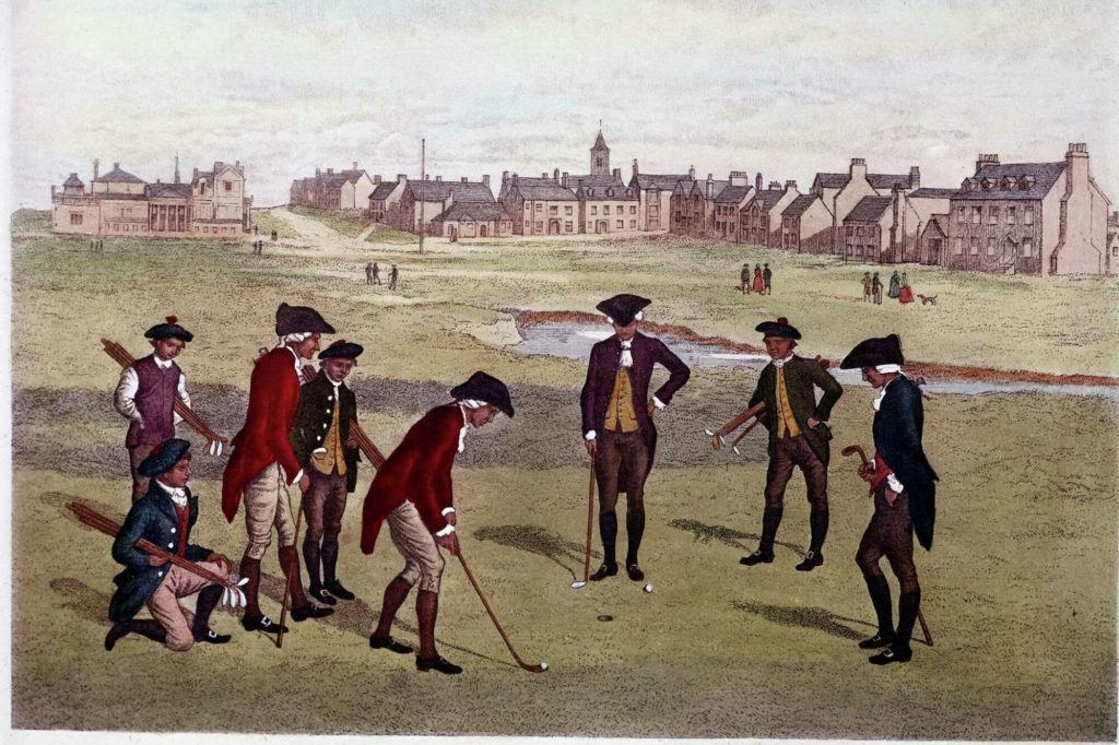 A group of 18th century gentlemen wearing tailcoats, breeches, boots and tricorn hats surround a putting green and hole watching as one man with a golf club prepares to sink his ball. In the background can be seen building of St. Andrews, Scotland.